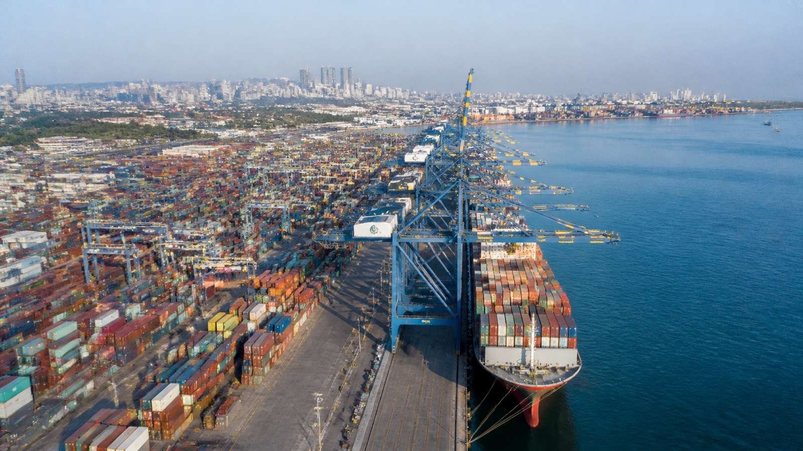 Container port with ship-to-shore cranes loading a container ship (illustration)